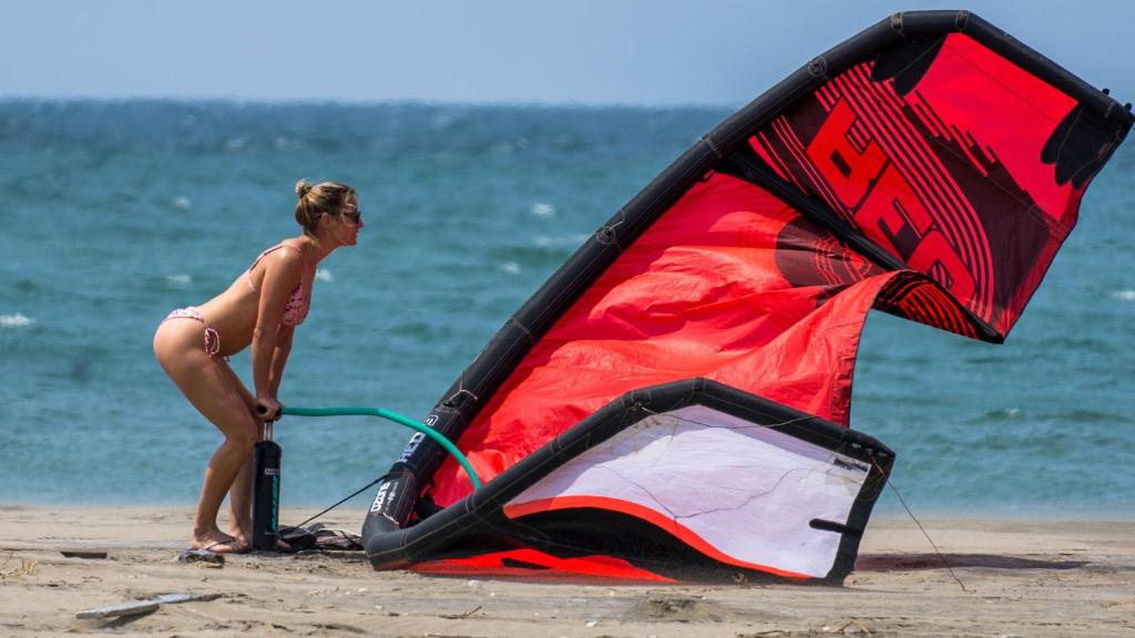 Eine Frau steht neben einem Drachen am Strand in der Unterkunft Kite Hotel Máncora - Beach & Gym in Máncora