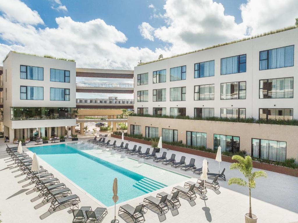 une image d'un bâtiment avec une piscine et des chaises dans l'établissement Hotel Faranda Single 1 Punta Cana - Adults Only, à Punta Cana