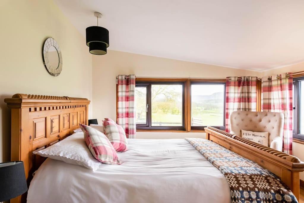a bedroom with a bed and a chair and windows at The Retreat in Llanrhaeadr-ym-Mochnant