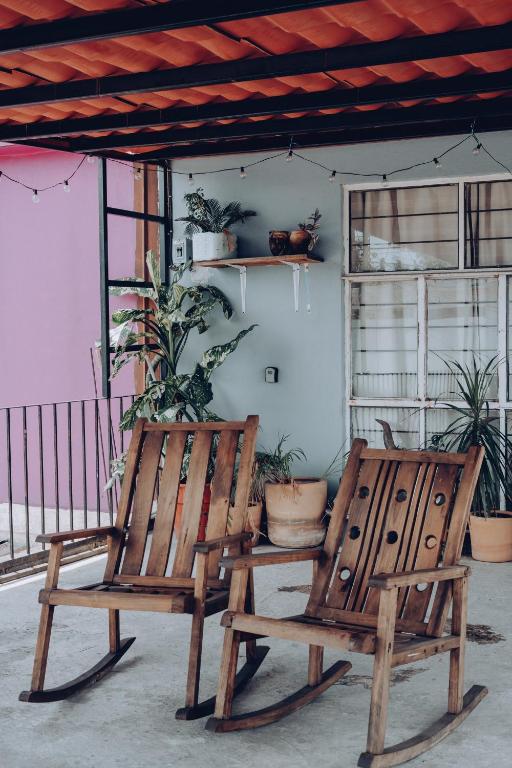2 sillas de madera sentadas en un porche con plantas en Bonito departamento y centrico, en Lázaro Cárdenas