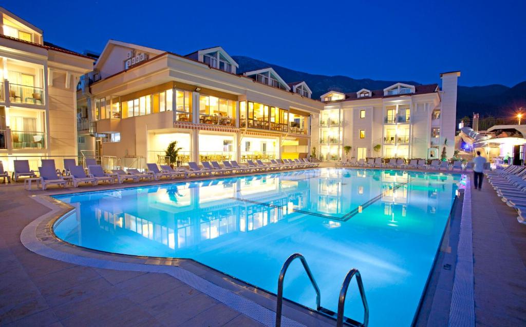 a large swimming pool in front of a hotel at night at Aes Club Hotel in Oludeniz