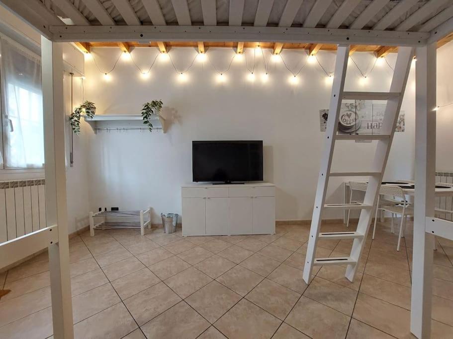 een woonkamer met een televisie en een ladder bij Smile Home! Graziosa casa con parcheggio e giardino in Bovísio-Masciago Milanese