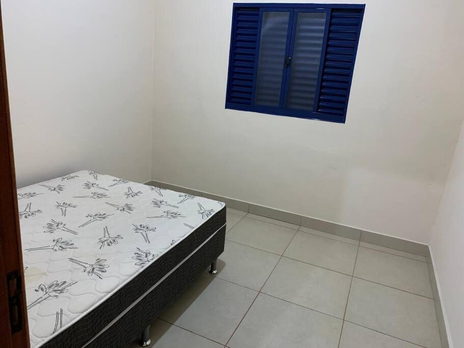 een slaapkamer met een bed en een blauw raam bij Casa para Temporada - Luminárias MG in Luminárias