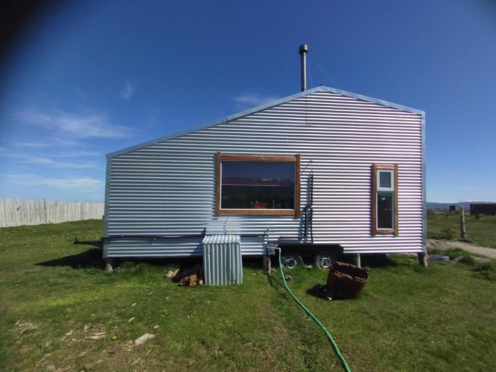 a small shed with a window on a grass field at Tyni house in Puerto Natales