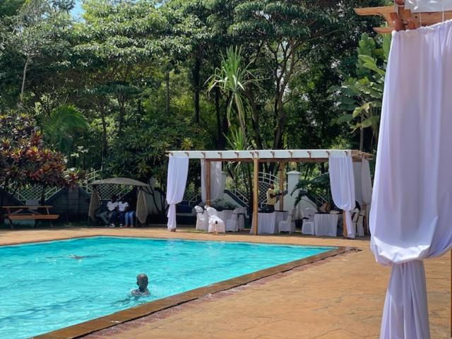 a person swimming in a swimming pool next to a tent at Jungle Green Resort, Kiutine in Meru