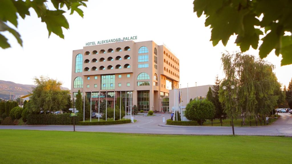 budynek z zielonym parkiem przed nim w obiekcie Aleksandar Palace Hotel Congress Center & SPA w mieście Skopje