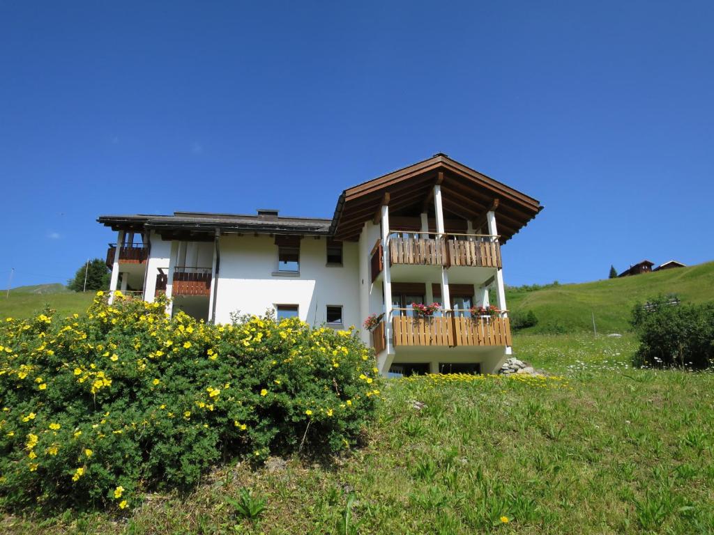 ein Haus mit einer Terrasse auf einem Hügel in der Unterkunft Chli Alpa A1 in Arosa