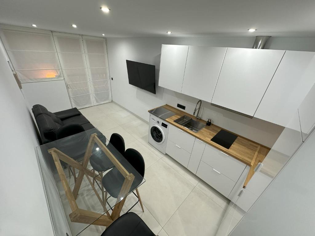 eine Küche mit weißen Schränken, einem Tisch und einer Mikrowelle in der Unterkunft Fuente Dulce in Orzola