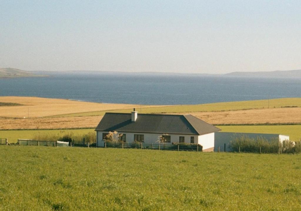 a house in a field next to the water at Kisumu in Orkney