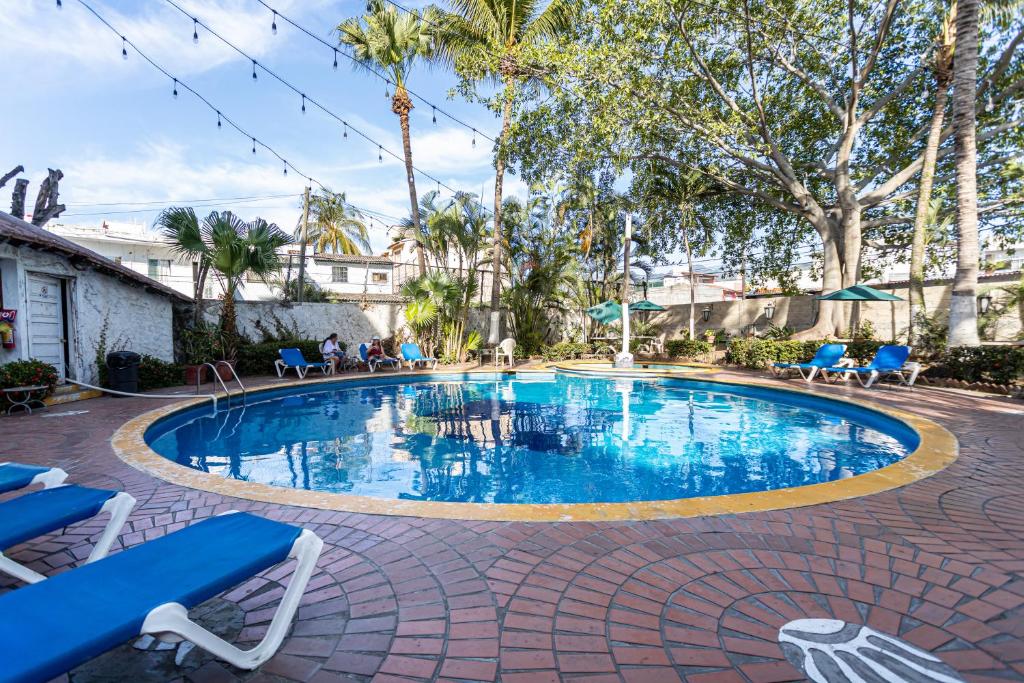 une grande piscine avec des chaises et des arbres bleus dans l'établissement Soy Local Puerto Vallarta, à Puerto Vallarta