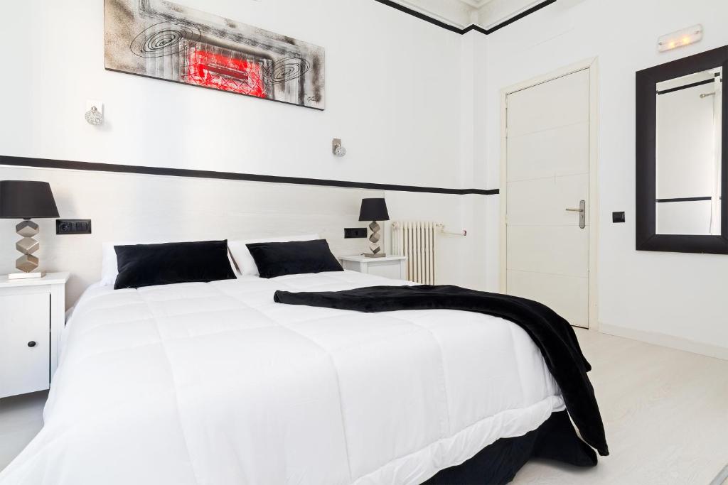 a white bedroom with a white bed with a black blanket on it at Gran Via 63 Rooms in Madrid