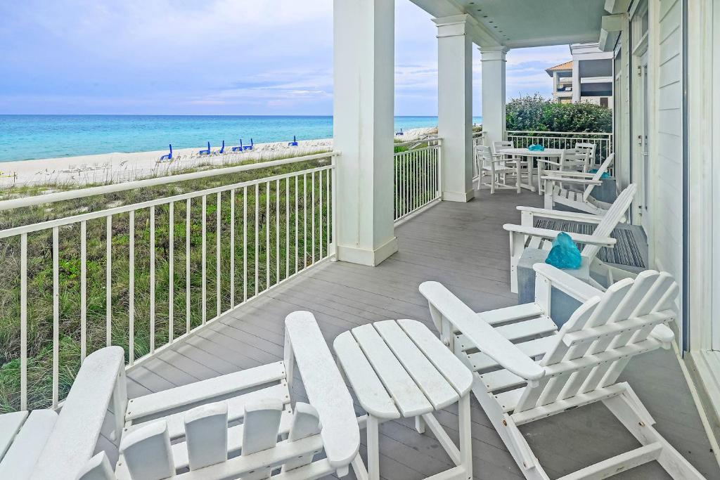 a porch with white chairs and tables and the beach at Carillon Beach- The White House in Carillon Beach