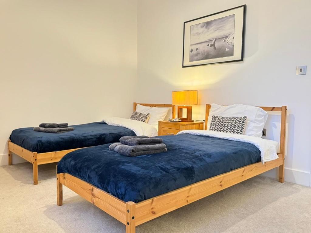 two beds in a room with blue blankets on them at Cozy Entire Flat with Gated Parking- Contractors, Family, Groups in Reading