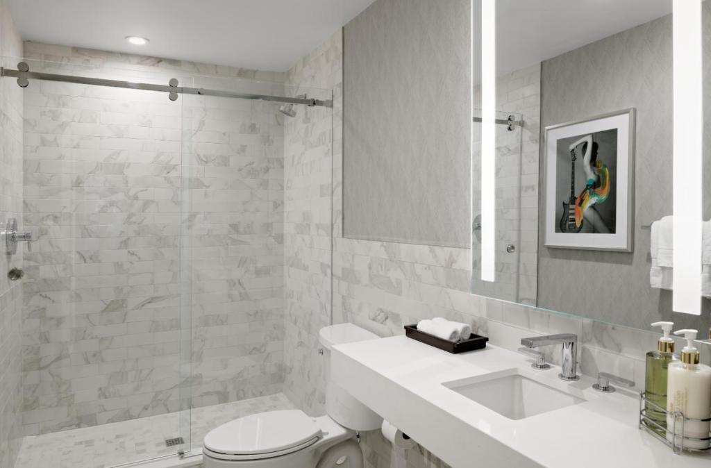 a bathroom with a sink and a toilet and a mirror at Le Parc at Melrose in Los Angeles