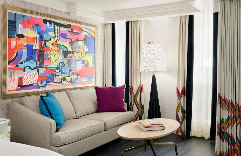 a living room with a couch and a colorful painting at Le Parc at Melrose in Los Angeles