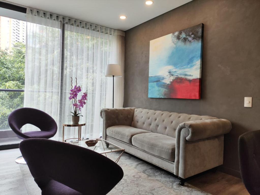 uma sala de estar com um sofá e duas cadeiras em Tropical Confort suite Poblado welcome breakfast em Medellín