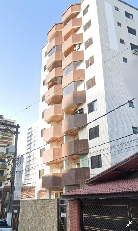 a tall white building with balconies on it at Apartamento praia Aviação in Praia Grande