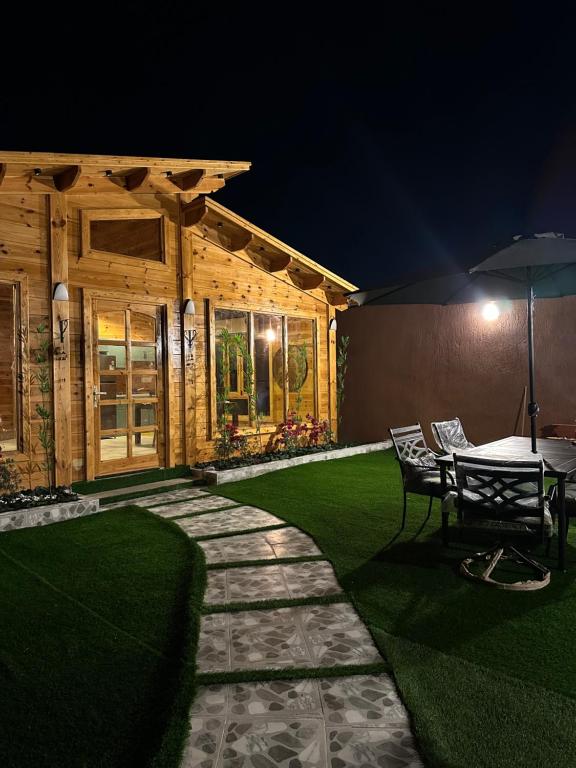 a patio with a table and an umbrella at night at كوخ السعاده happiness hut in Thuwal