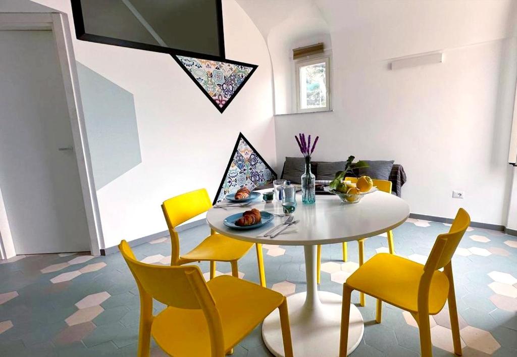 a dining room with a white table and yellow chairs at La mia casetta al mare in Minori