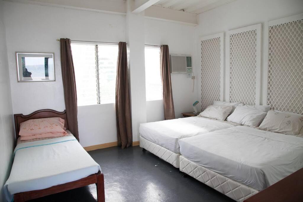 a white bedroom with two beds and a window at Villa Elena Guimaras in Buenavista