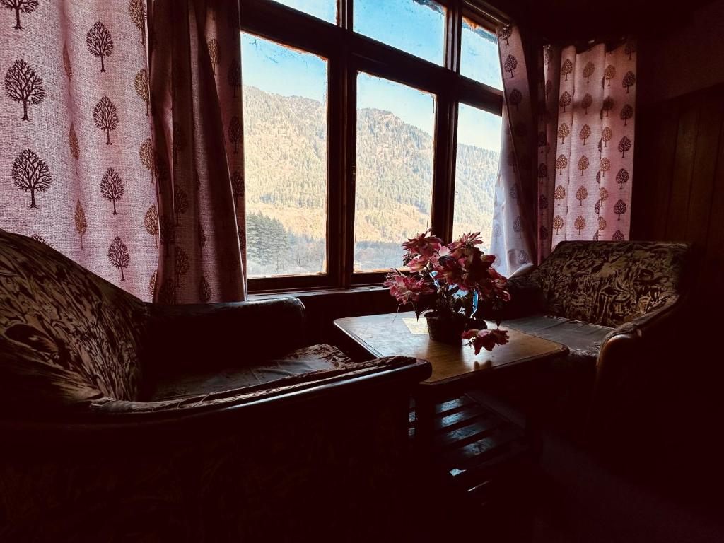 a living room with a couch and a table and a window at WooibHotels The Daulat Manali in Manāli