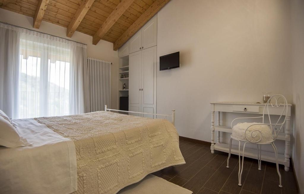 a white bedroom with a bed and a window at B&B Il Barsot in Pettenasco