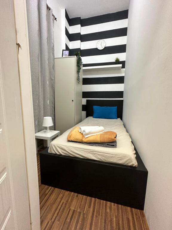 Dormitorio pequeño con cama con pared a rayas en Fancy Partition Room Near Mashreq Metro / SZ Road en Dubái
