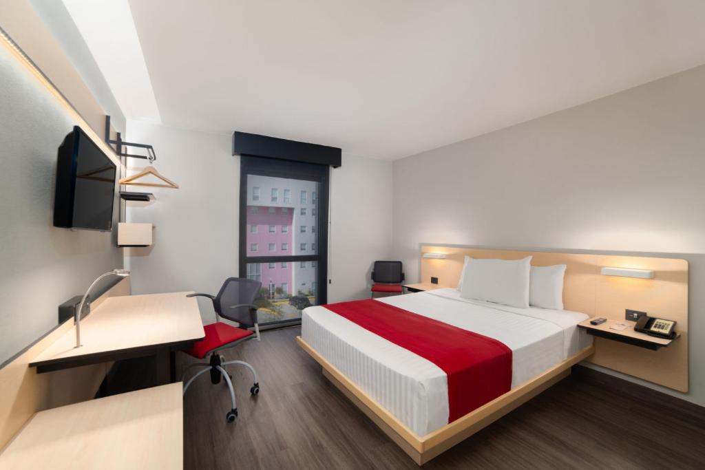 a hotel room with a bed and a desk and a chair at City Express by Marriott Silao Aeropuerto in Silao