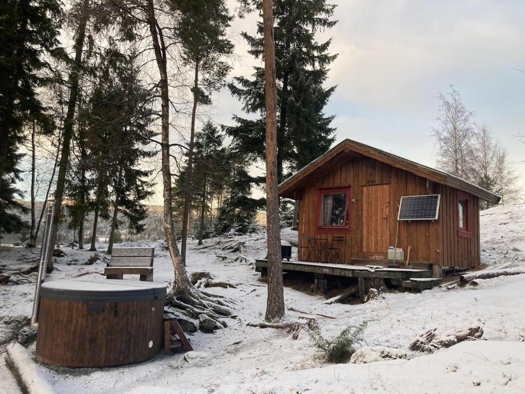 una pequeña cabaña de madera en la nieve con un banco en Typisk norsk off-grid hytte opplevelse, en Levanger
