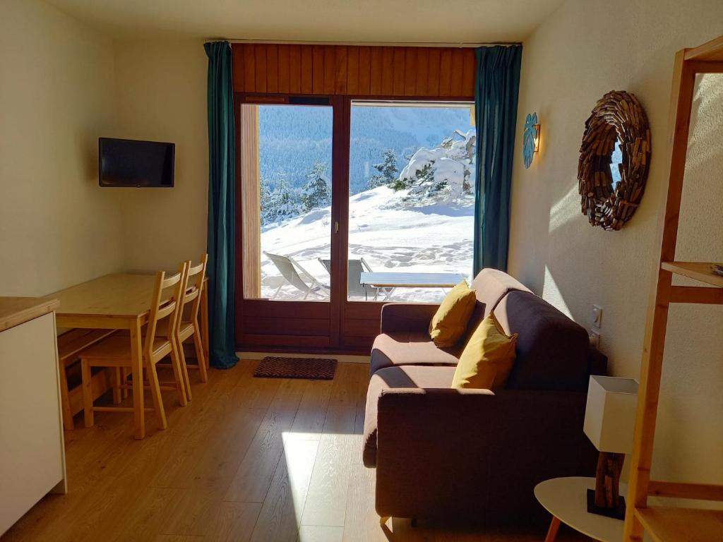 un salon avec un canapé, une table et une fenêtre dans l'établissement Appartement La Canopée, à Gresse-en-Vercors