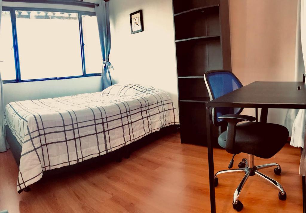 a small bedroom with a bed and a desk and a chair at Alojamiento Cuarto Espiral in Manizales