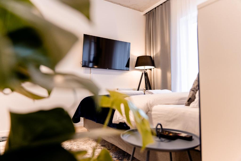 a living room with a couch and a tv on the wall at Hop & Lulu Delux Apartments in Goleniów
