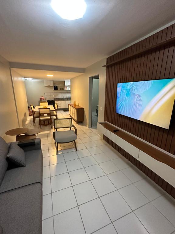 uma sala de estar com uma grande televisão de ecrã plano na parede em Apartamento 80 m2 com dois quartos - João Pessoa em João Pessoa