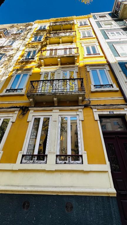 a yellow building with windows and a balcony at Suites Luciano Cordeiro in Lisbon