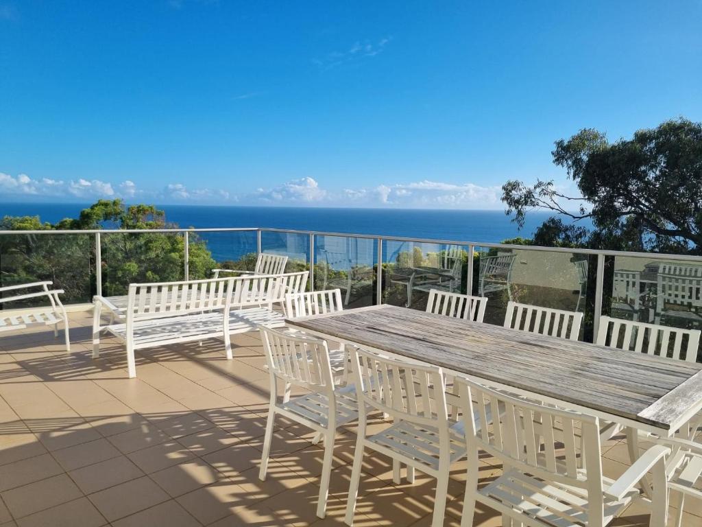 a wooden table and chairs on a deck with the ocean at Rainbow Ocean Palms Resort in Rainbow Beach