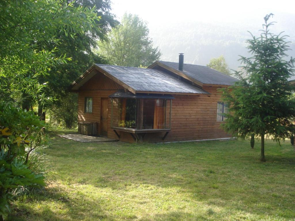 ein kleines Holzhaus mit einer Veranda im Hof in der Unterkunft Cabañas Pichares in Caburgua