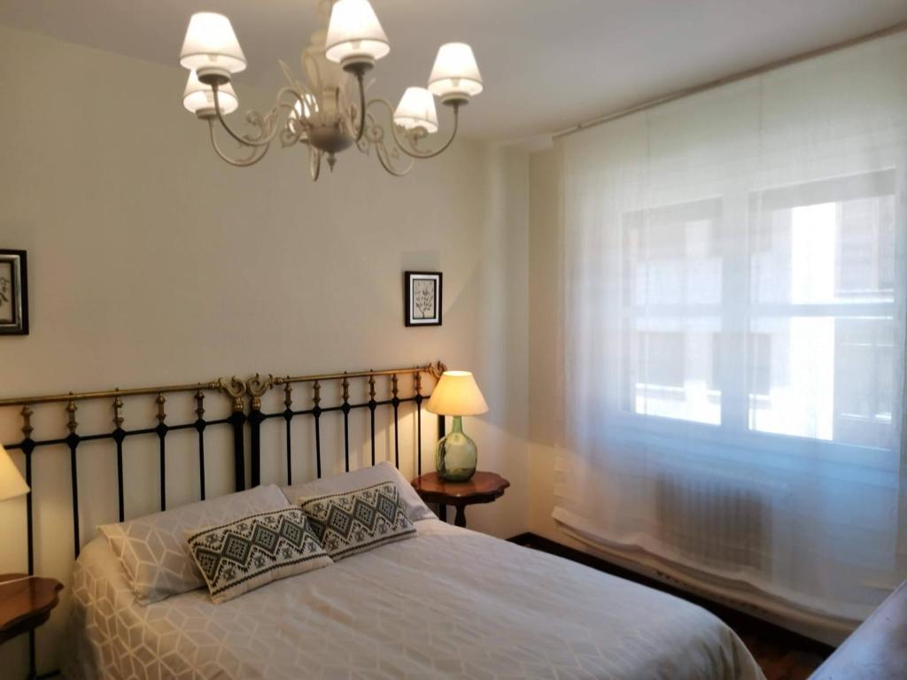 a bedroom with a bed and a window with a chandelier at Apartamento Estriva in Ezcaray