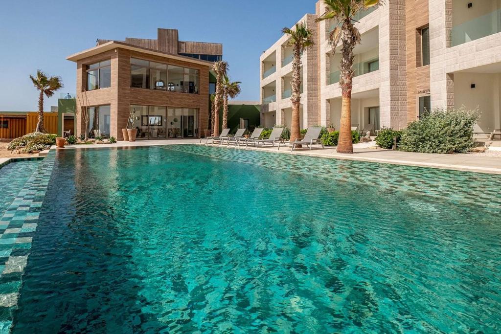 a swimming pool in front of a building with palm trees at Dakhla South Bay in Dakhla