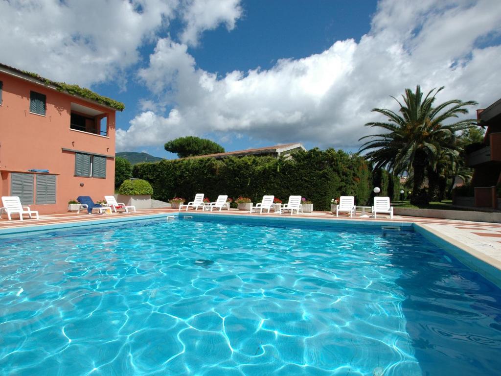a large swimming pool with chairs and a building at Residence Maricampo in Marina di Campo