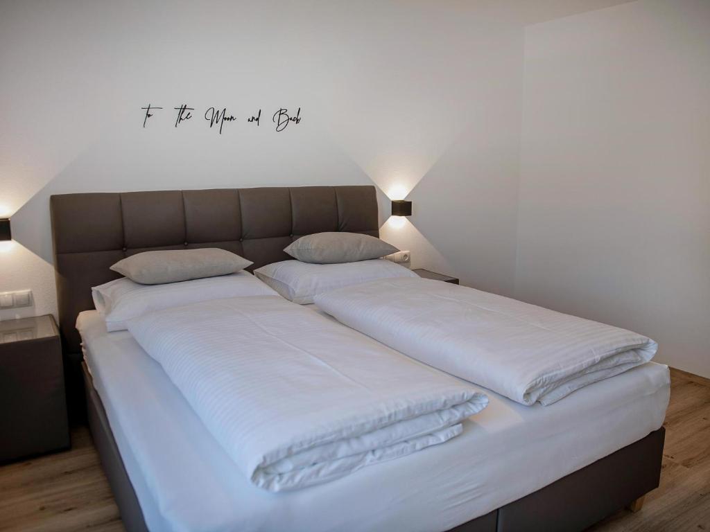 Elle comprend un grand lit avec des draps blancs et un bureau sur le mur. dans l'établissement Green Residence L II, à Wildschönau