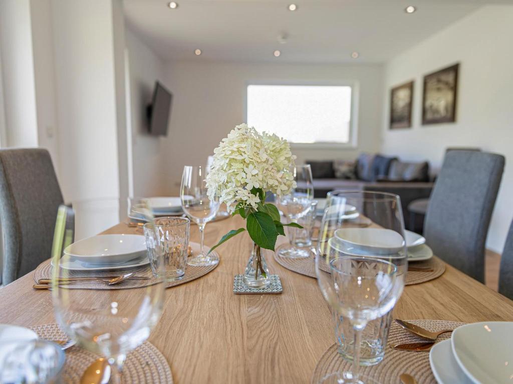 a table with glasses and a vase of flowers on it at Green Residence XL in Wildschönau