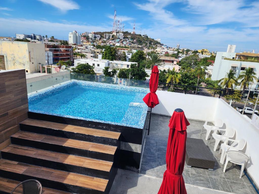 een zwembad op het dak van een gebouw met twee parasols bij Dpto Playa Centro Malecón Plza Machado¡Promoción! in Mazatlán
