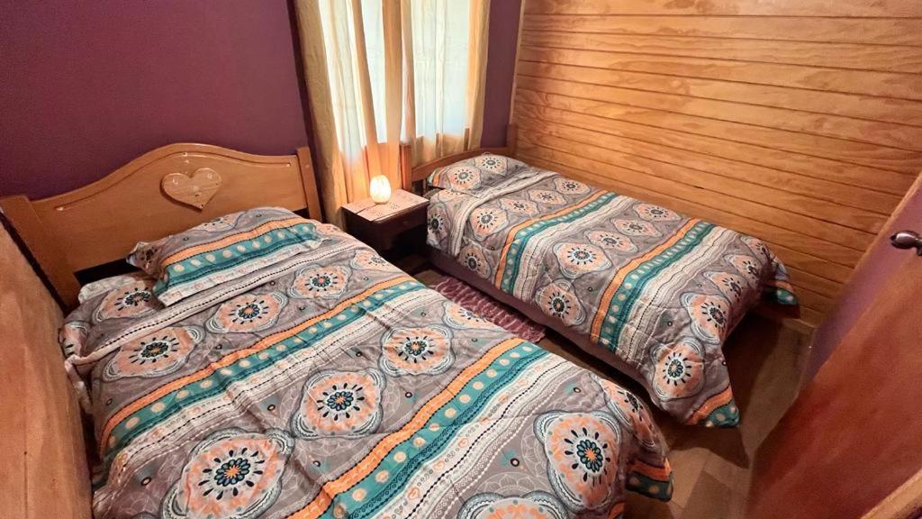 dos camas sentadas una al lado de la otra en un dormitorio en Cabaña Loremar canaan, en Chonchi