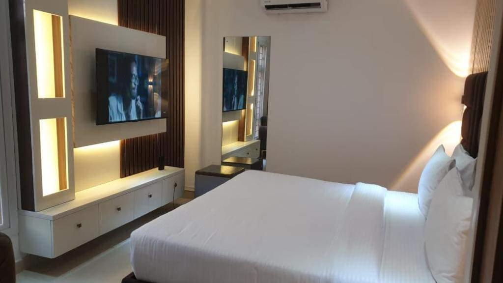 a bedroom with a white bed and a television at Dozubel Hotel in Abuja