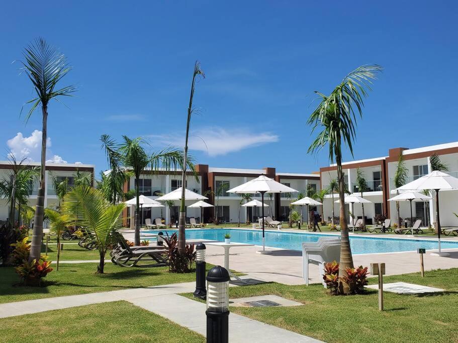 a resort with a pool and palm trees and umbrellas at Escapada en Boca chica in Boca Chica