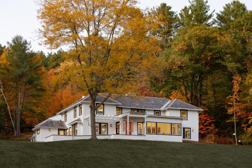a white house with a tree on a hill at Shelburne Springs Hotel in Shelburne Falls