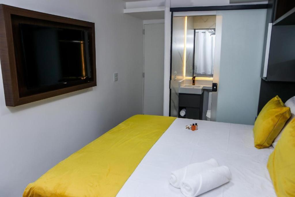 a bedroom with a large bed with a yellow blanket at Pousada do Braga in Cabo Frio