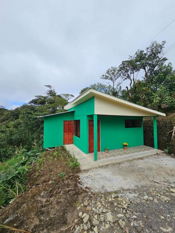 a green house with a red door on a hill at Aves del Paraíso in Tilarán
