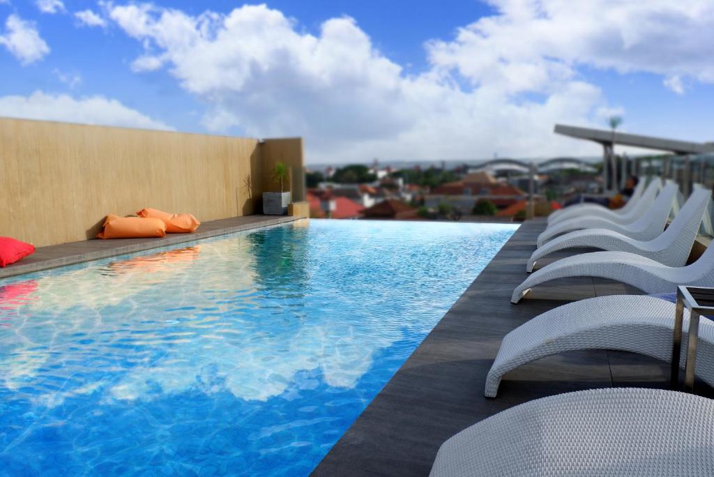 a swimming pool on top of a building with chairs at Stark Boutique Hotel and Spa in Kuta