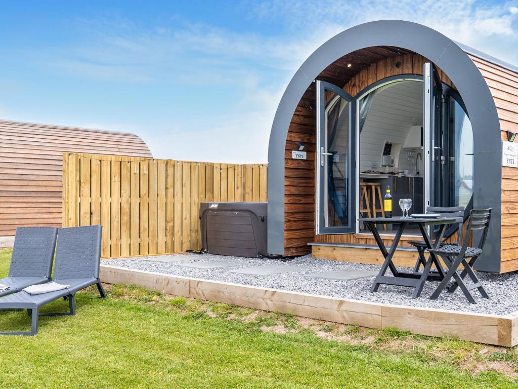 a circular building with a table and chairs in a yard at Ynys Pod - Uk46078 in Gwbert